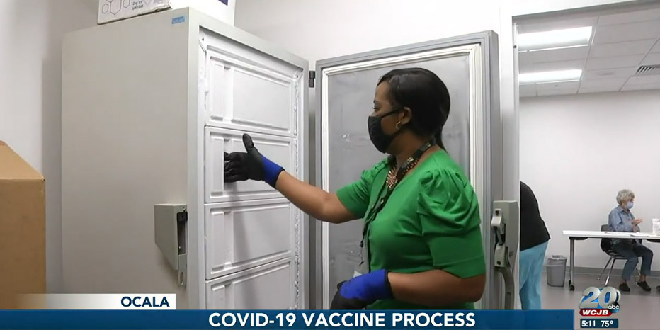 A healthcare worker opens a vaccine refrigeration unit.